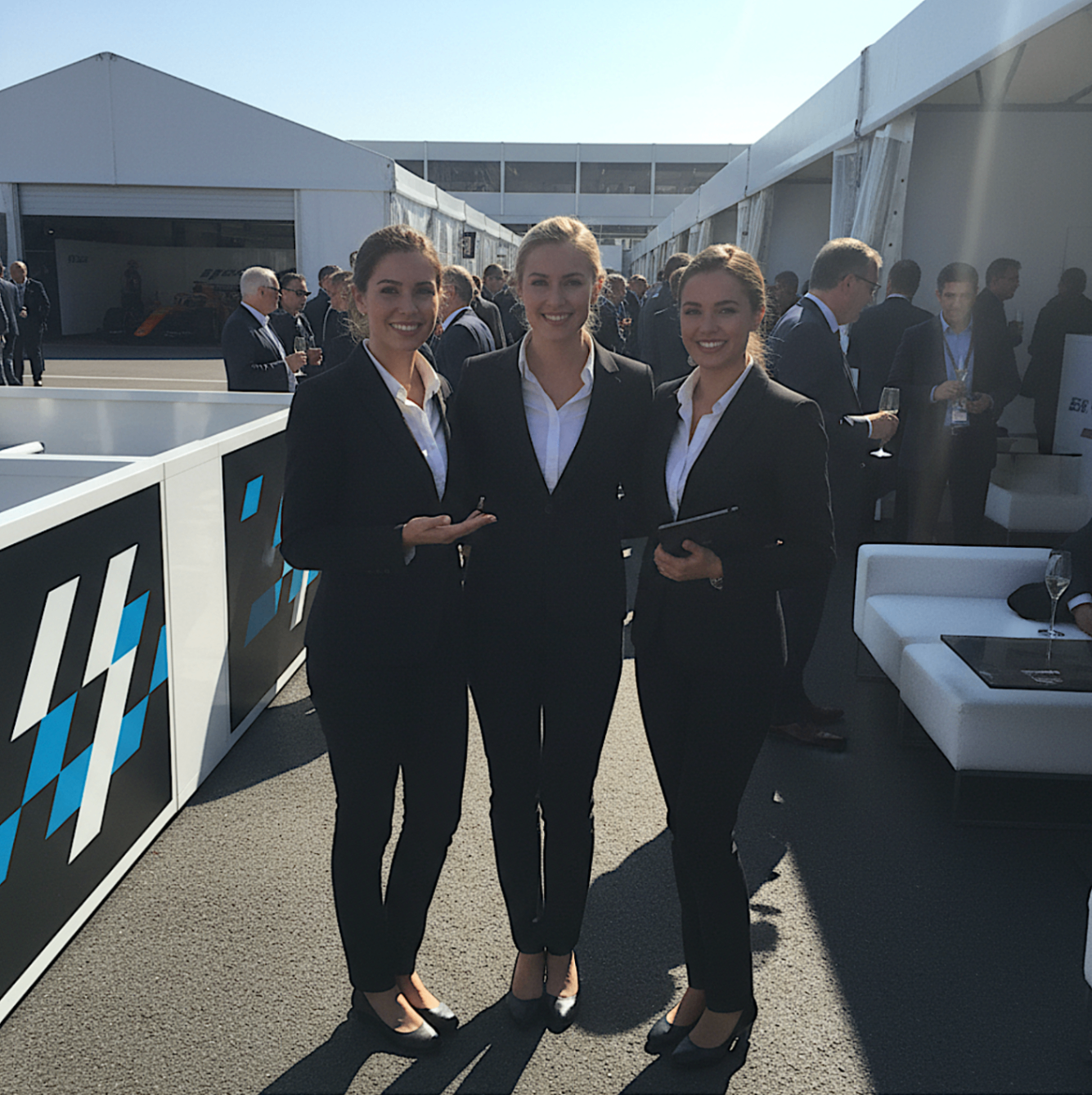 Three hospitality staff in formal black tailoring at a premium event venue